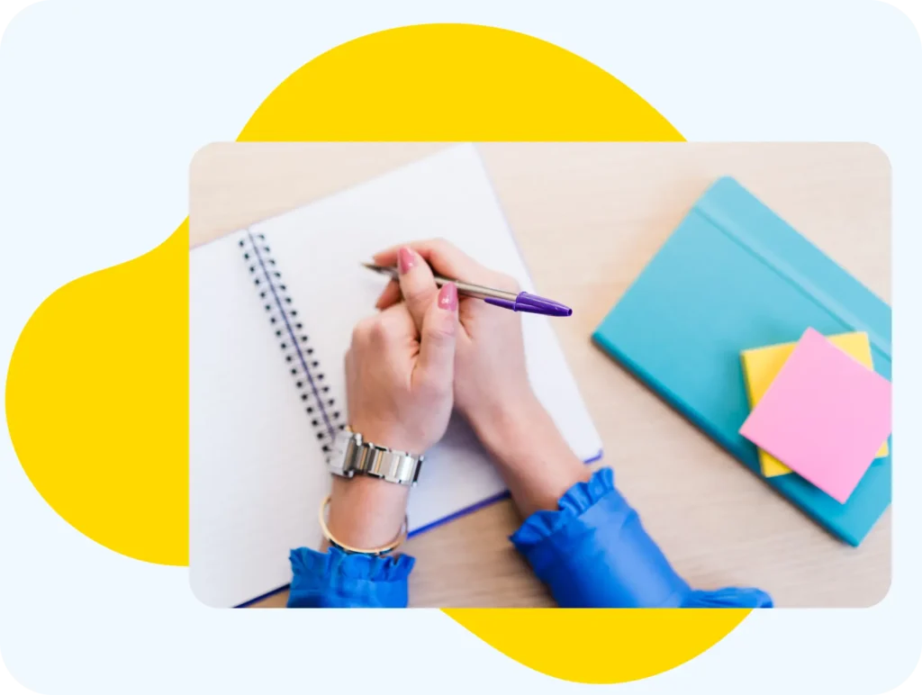 A pair of hands holding a pen above a notebook